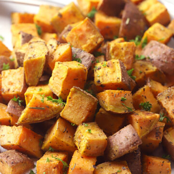 White plate filled with cubed roasted sweet potatoes.