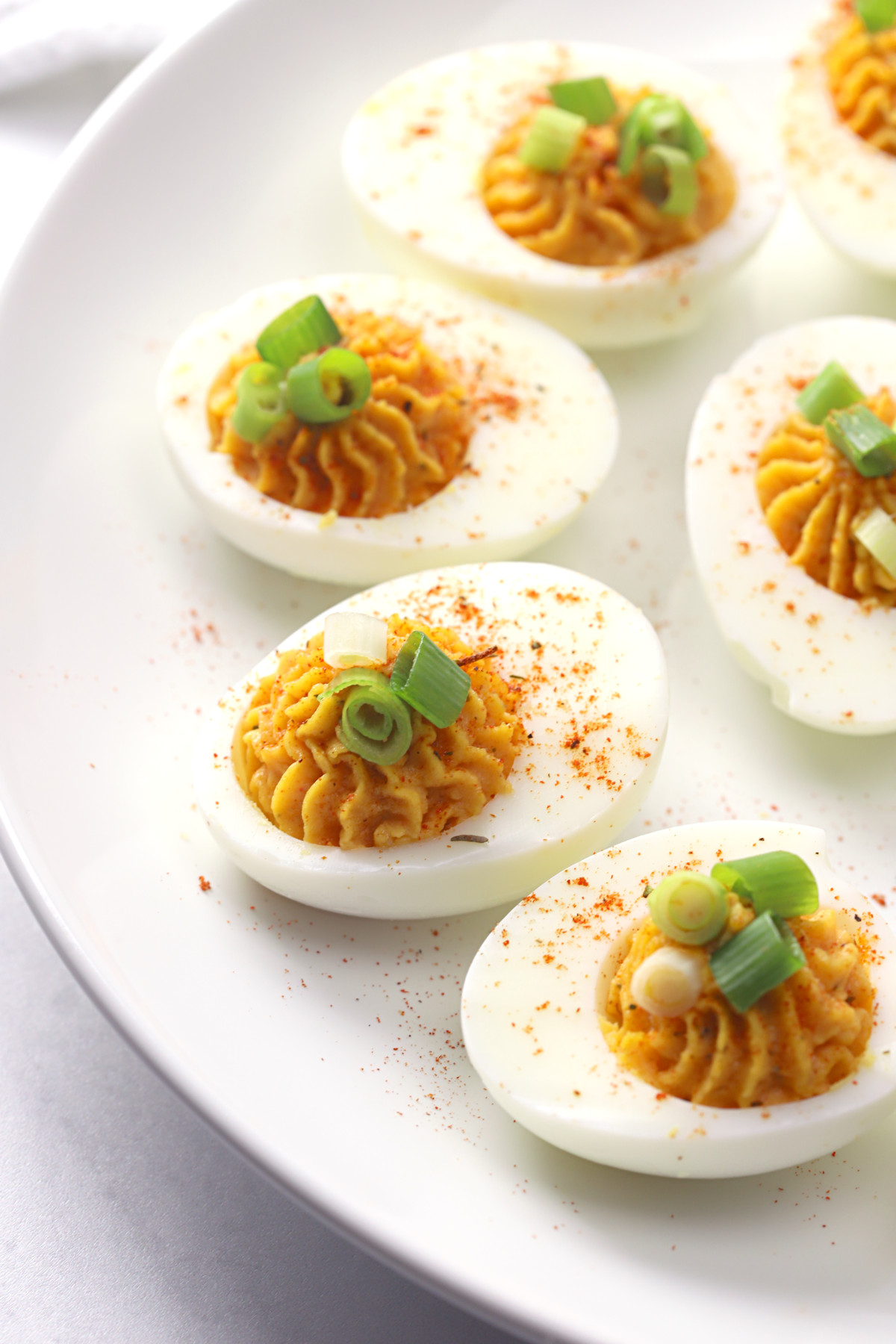 Spicy cajun deviled eggs on a white plate.