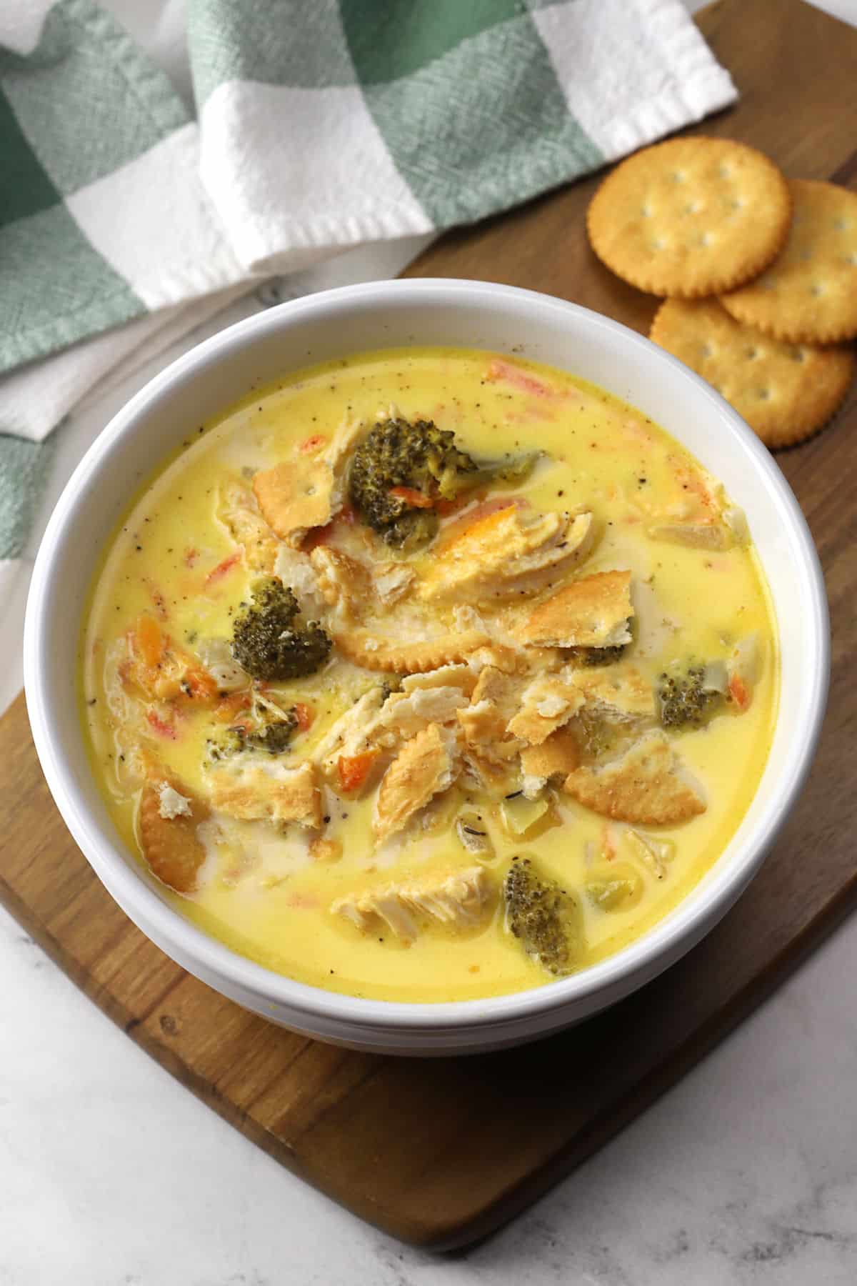 A white bowl filled with chicken broccoli cheese soup topped with crumbled crackers.