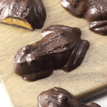 Candy chocolate frogs on a wooden cutting board.