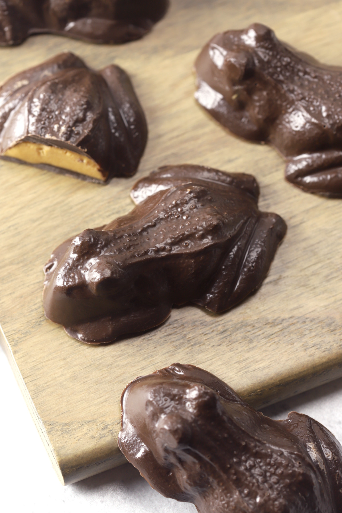 Candy chocolate frogs on a wooden cutting board.