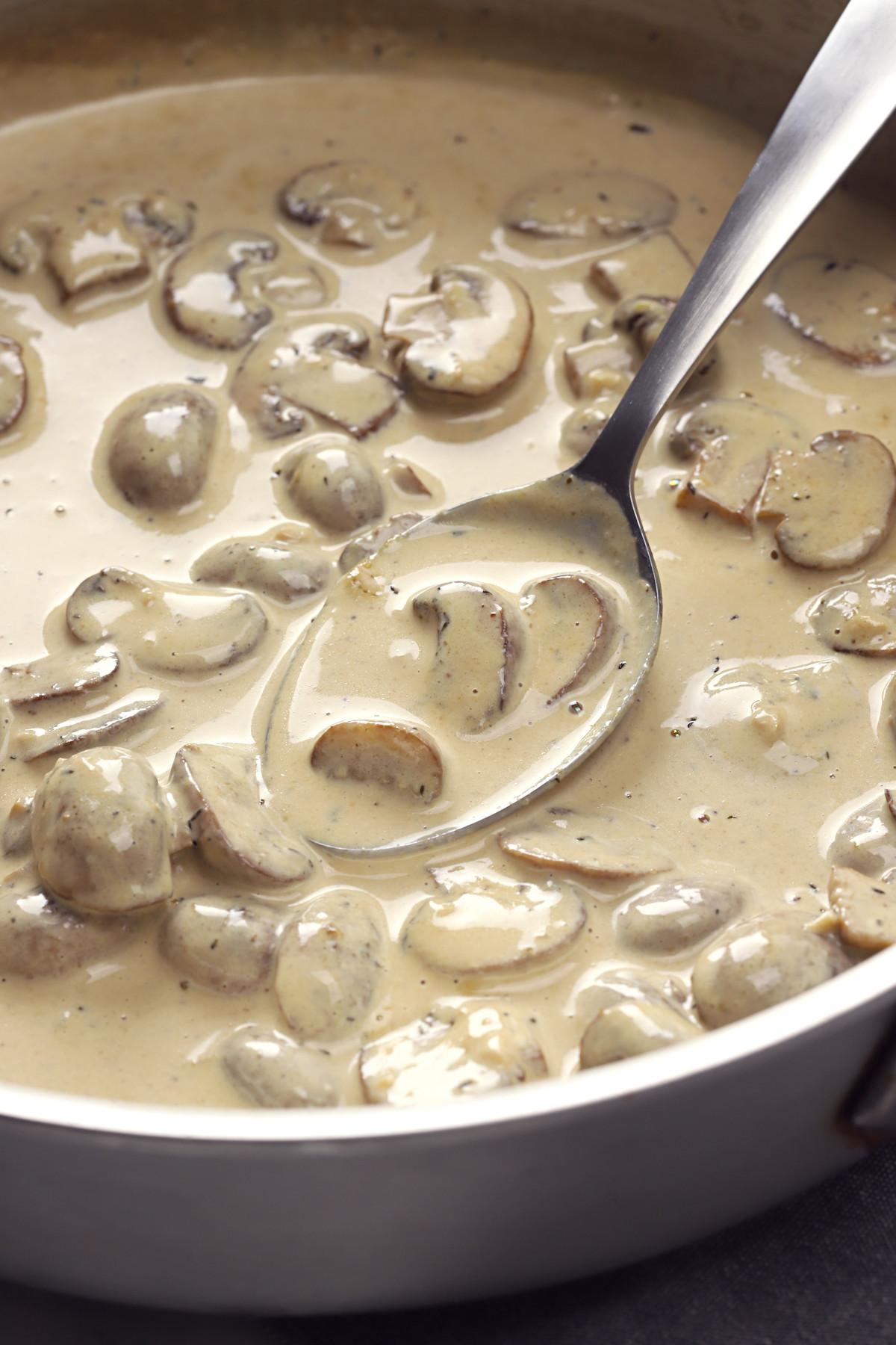 Creamy mushroom sauce in a saute pan with a spoon.