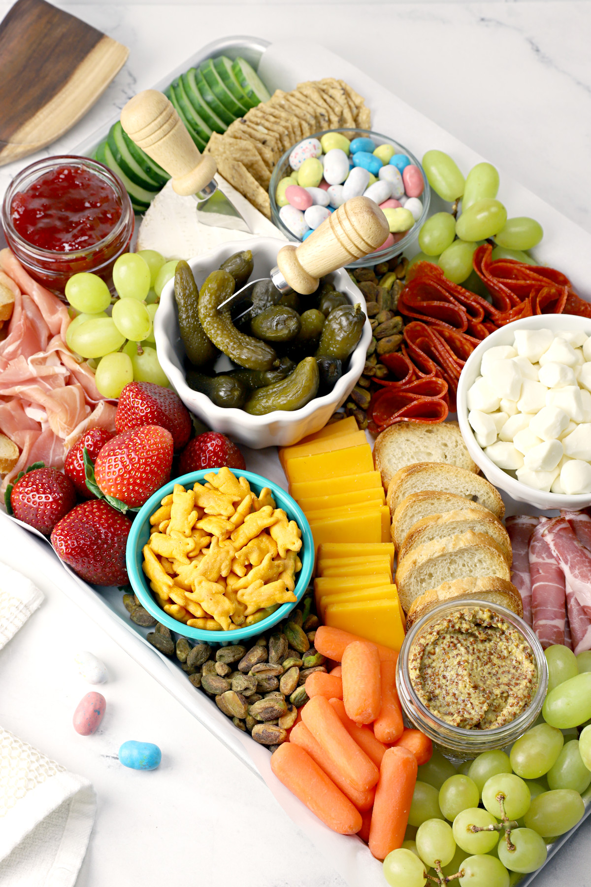 Meats, cheeses, crackers, and fruits set up on an Easter charcuterie board.