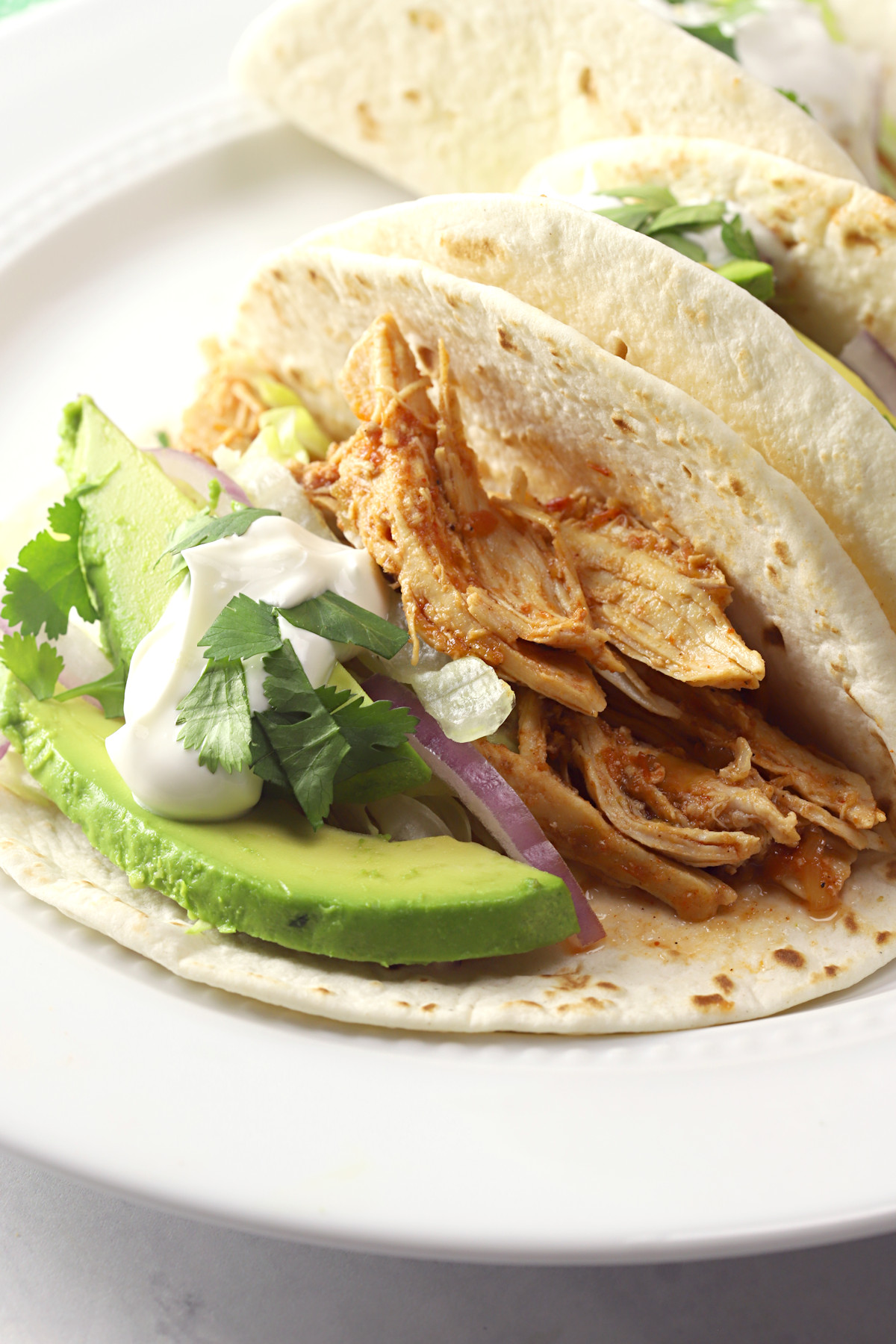 Flour tortilla filled with shredded chicken and taco toppings.