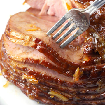 A fork serving slices of glazed ham.