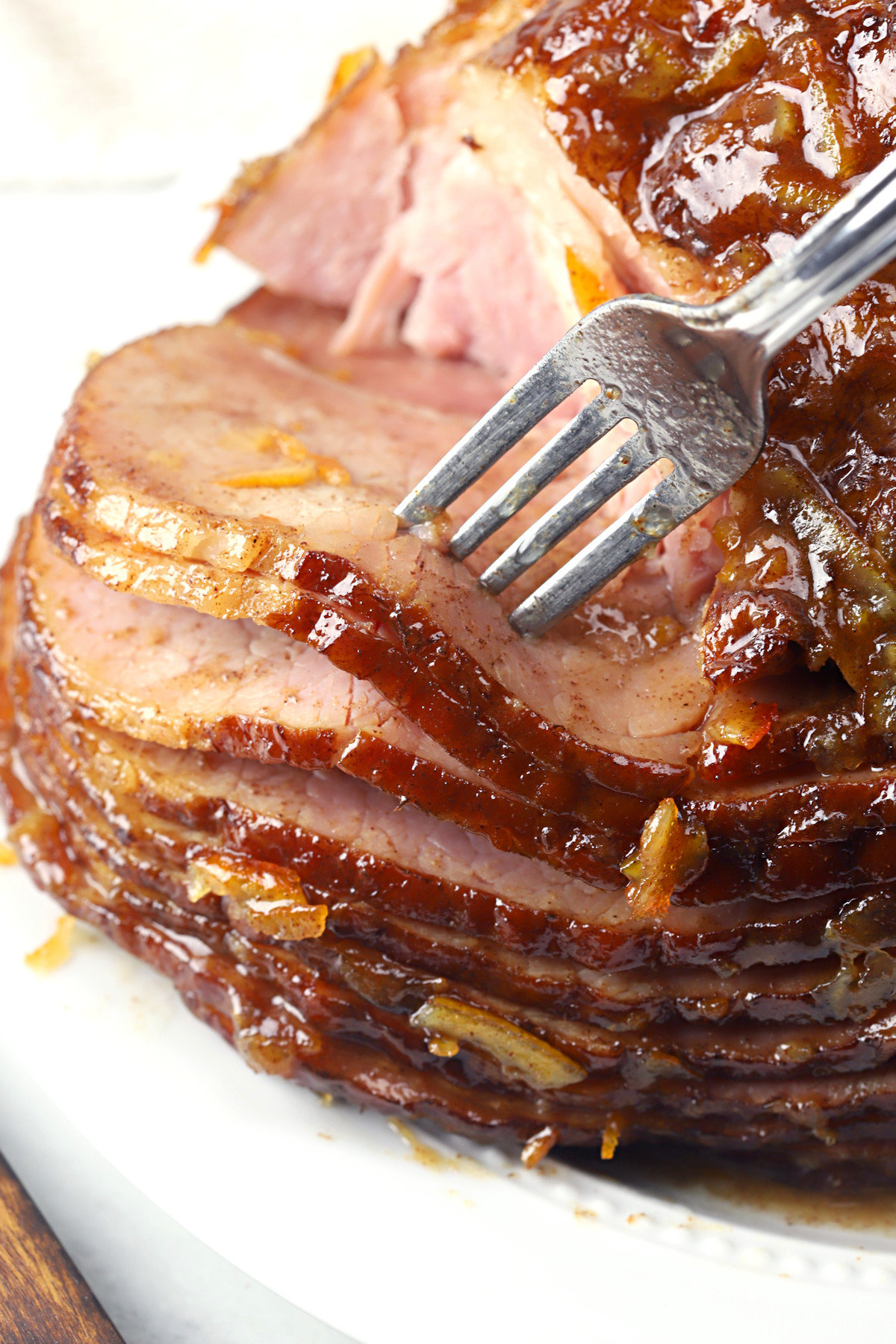 A fork serving slices of glazed ham.