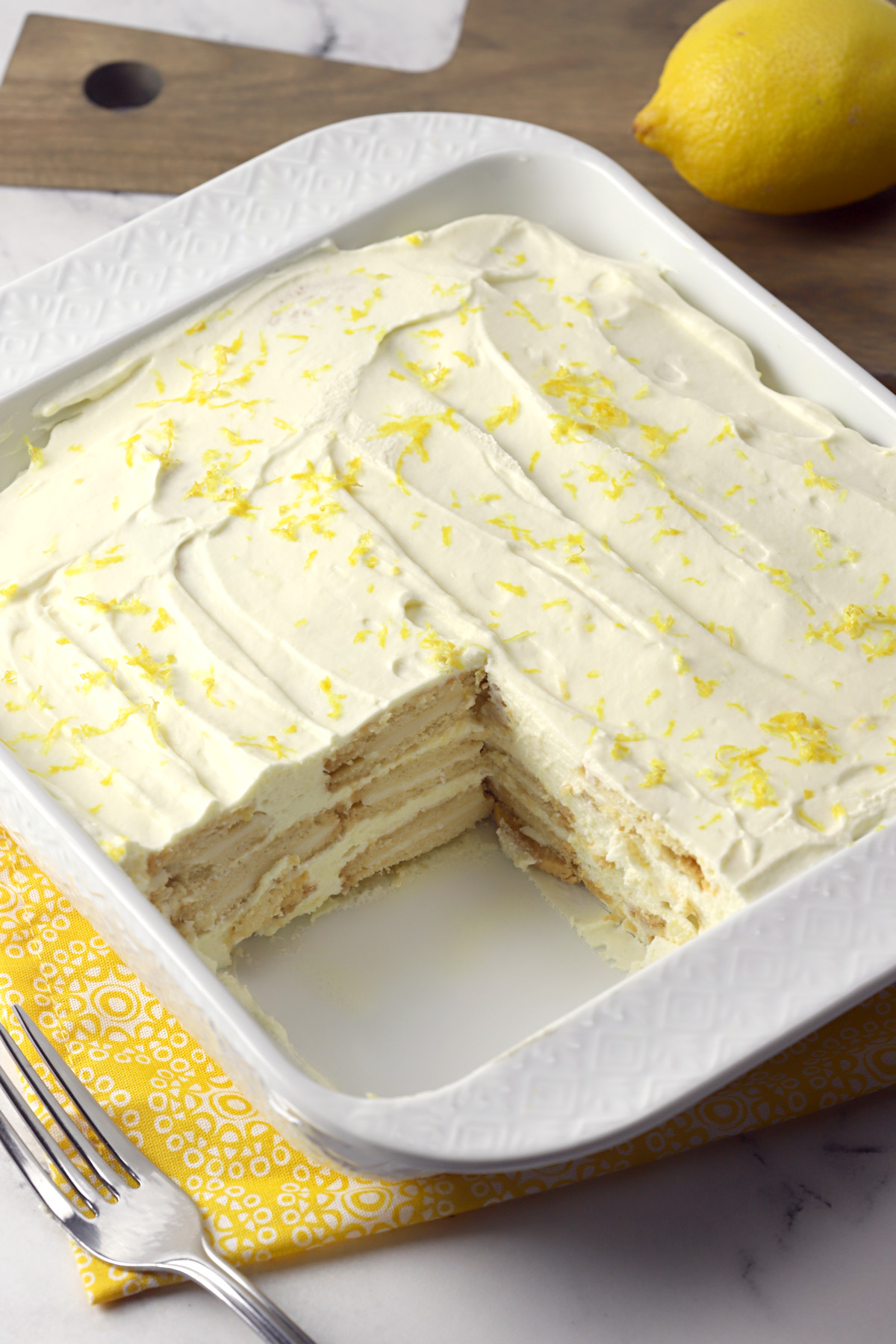 A slice taken from a lemon icebox cake in a white dish.