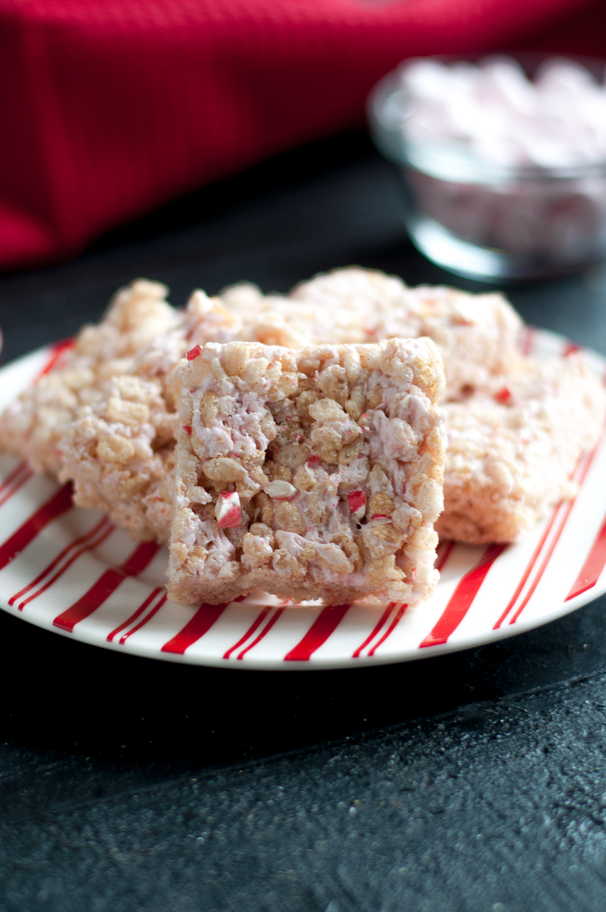 Peppermint rice krispies treats on a red striped plate.