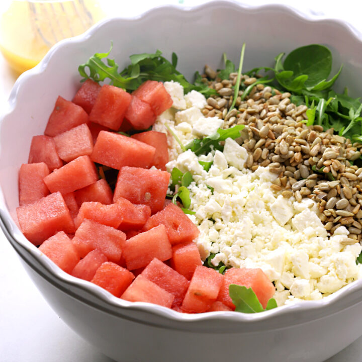 White bowl filled with watermelon, feta cheese, and sunflower seeds.