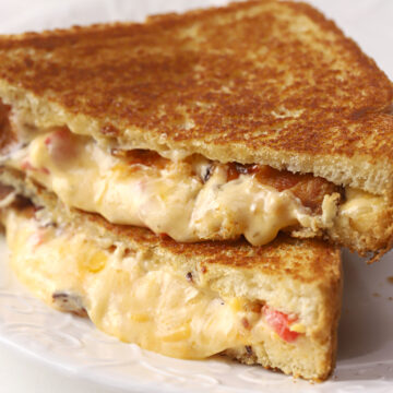 Melty pimento cheese sandwich sliced in half on a plate.