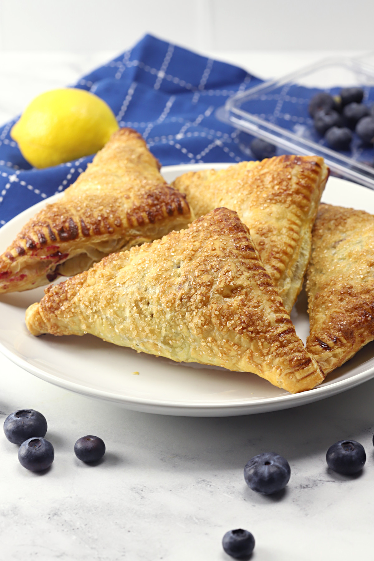 A serving plate filled with puff pastry blueberry turnovers.