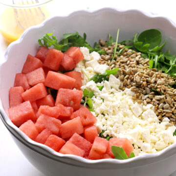 White bowl filled with watermelon, feta cheese, and sunflower seeds.
