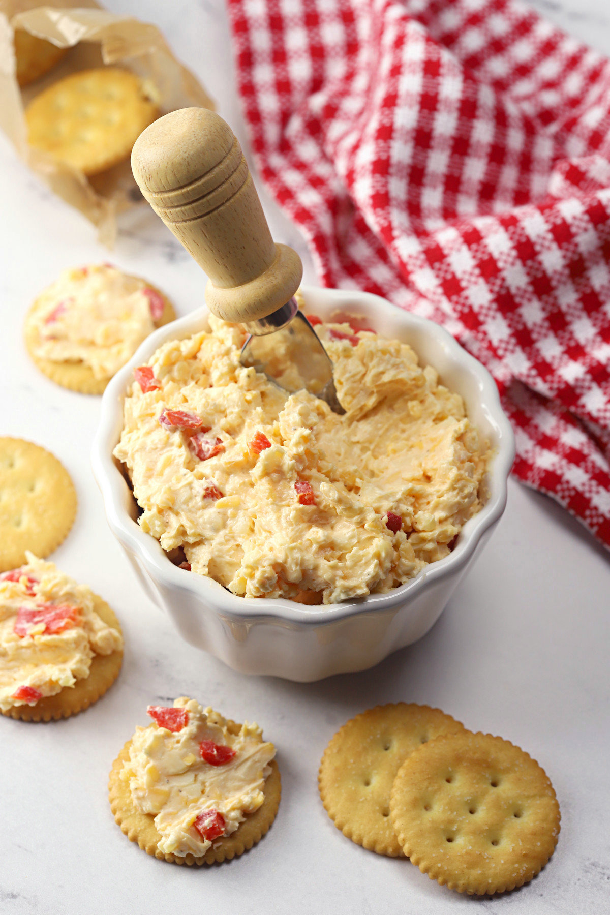 A bowl of pimento cheese with round crackers.