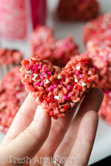 A hand holding up a heart shaped red velvet rice krispies treat.
