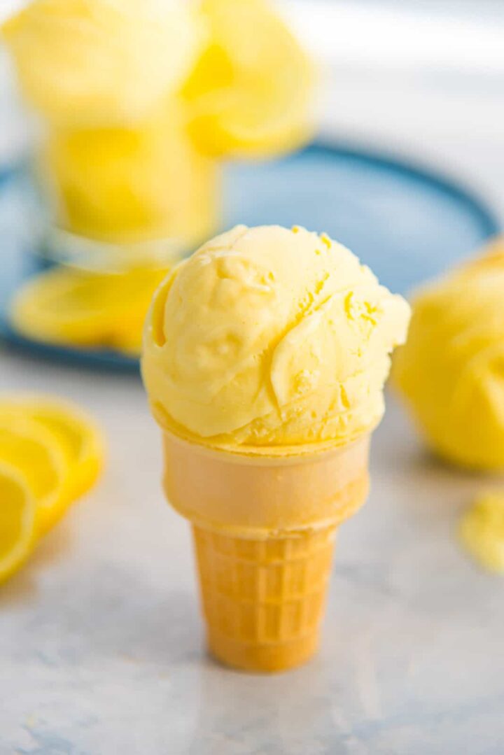 Ice cream cone topped with a scoop of lemon ice cream.