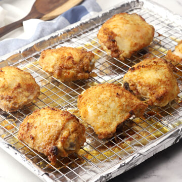 Crispy baked chicken thighs on a baking sheet.
