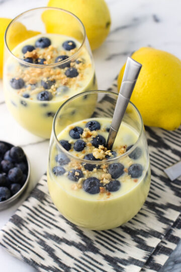 Glasses filled with lemon pudding and topped with blueberries.