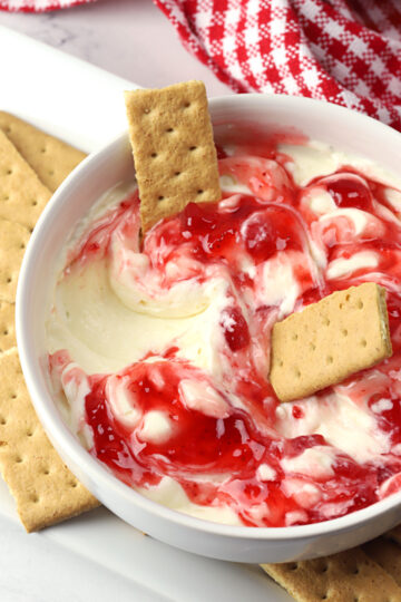 Graham crackers dipped in a bowl of strawberry cheesecake dip.
