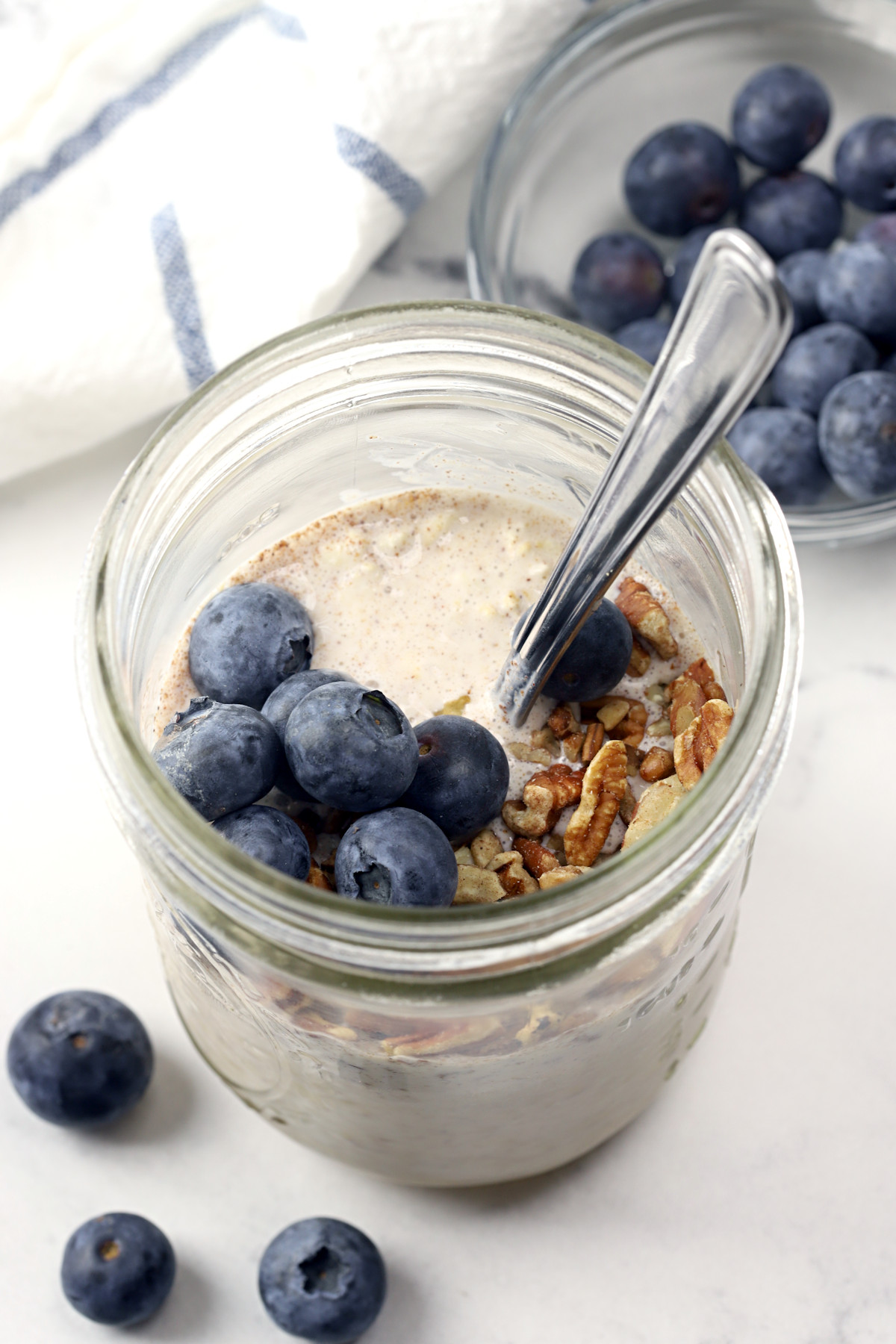 Overnight oats in a jar with blueberries and a spoon.