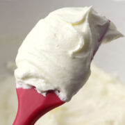 Red spatula covered in white frosting.
