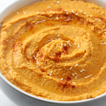 Paprika and olive oil drizzled on top of a bowl of hummus.