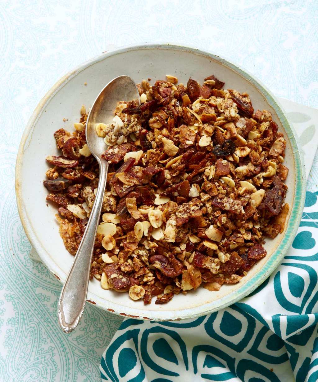 Granola in a bowl with a metal spoon.