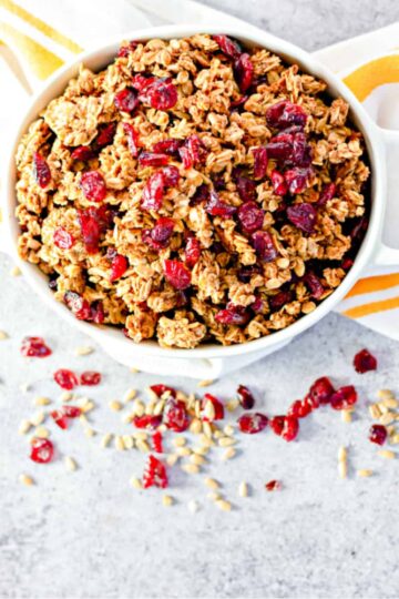 A white bowl filled with granola with cranberries.