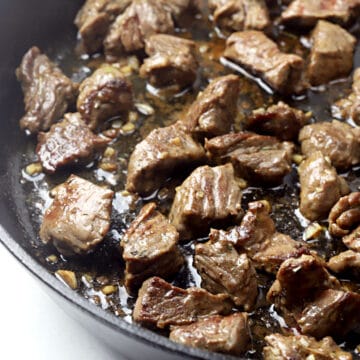 Cooked steak tips in a cast iron pan.