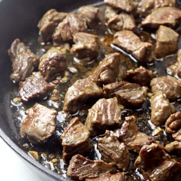 Cooked steak tips in a cast iron pan.