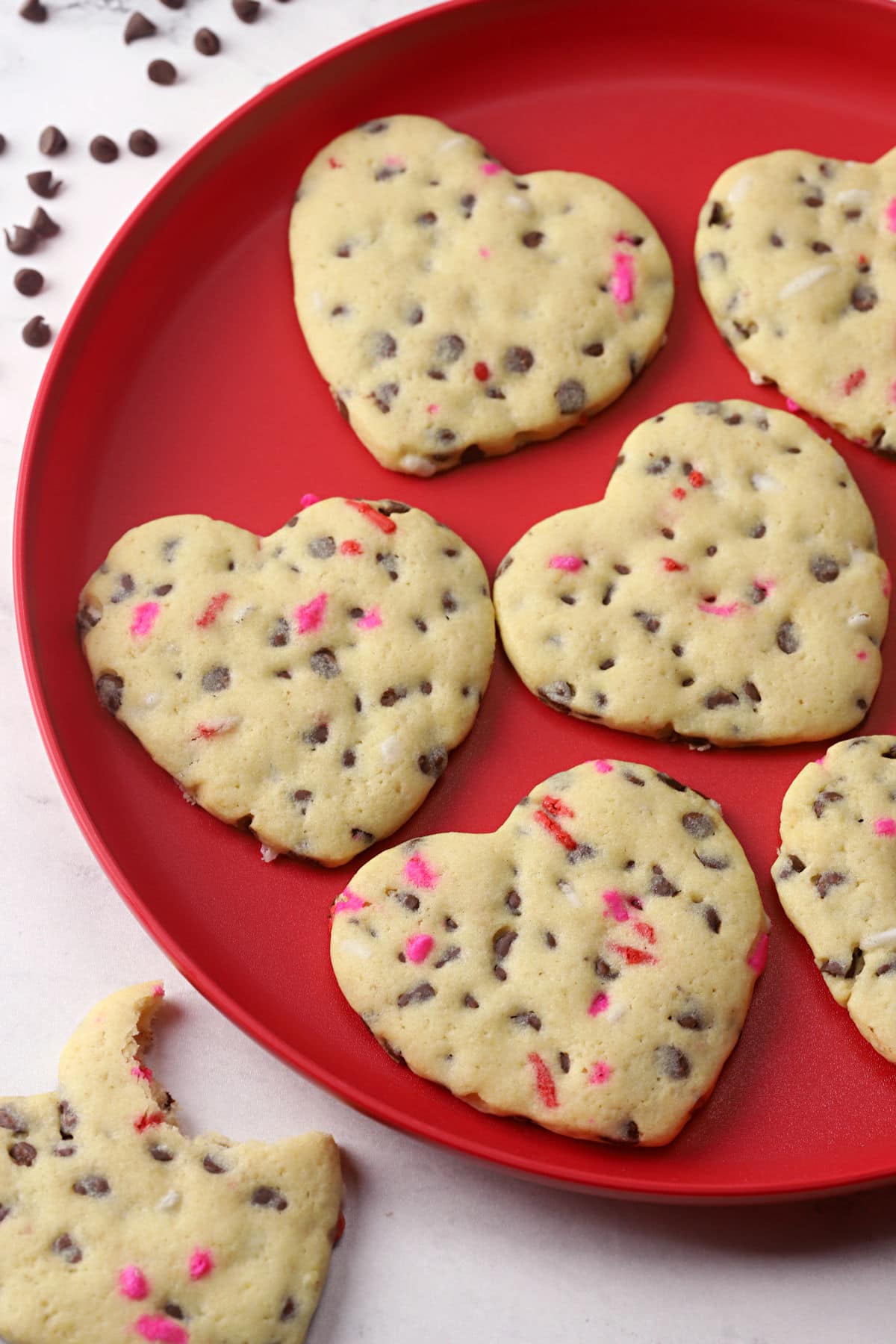 Heart shaped chocolate chip cookies on a red plate.