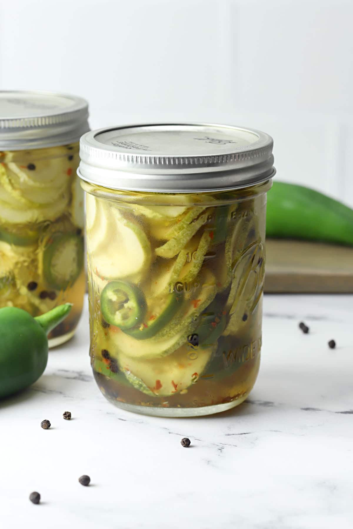 A glass jar filled with sweet and spicy pickles and jalapeno slices.