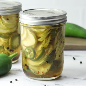 A glass jar filled with sweet and spicy pickles and jalapeno slices.