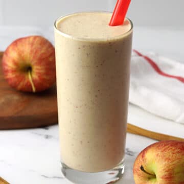 A glass filled with apple pie smoothie and a red straw.