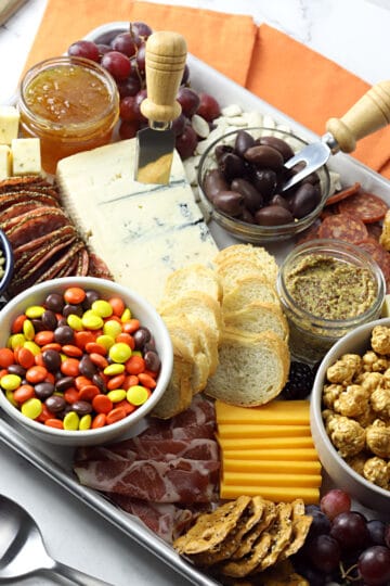 Close up of meats, cheeses, crackers, caramel corn, and candies on a Halloween charcuterie board.