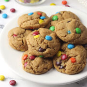 A white plate filled with small peanut butter cookies filled with colorful candies.