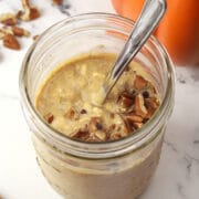 Glass jar filled with overnight oats topped with pecans.