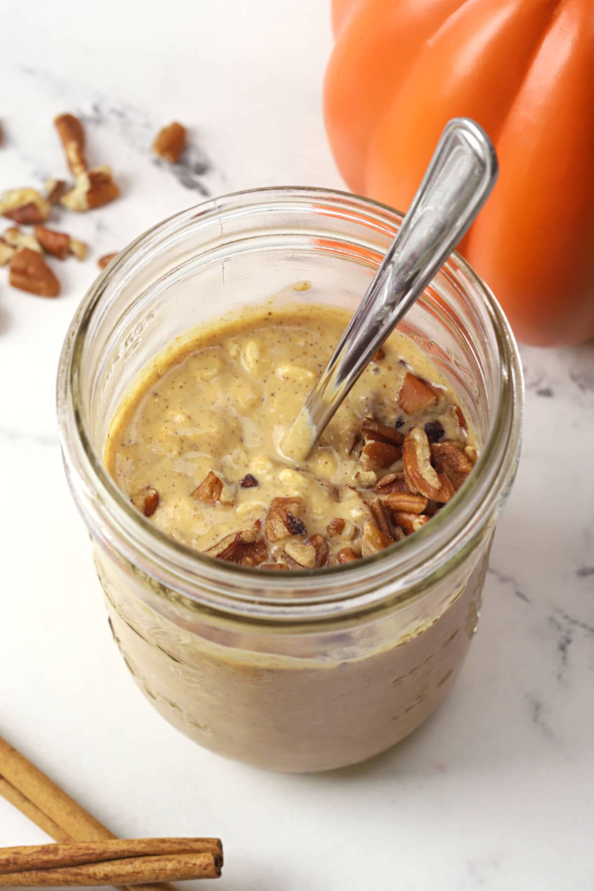 Glass jar filled with overnight oats topped with pecans.