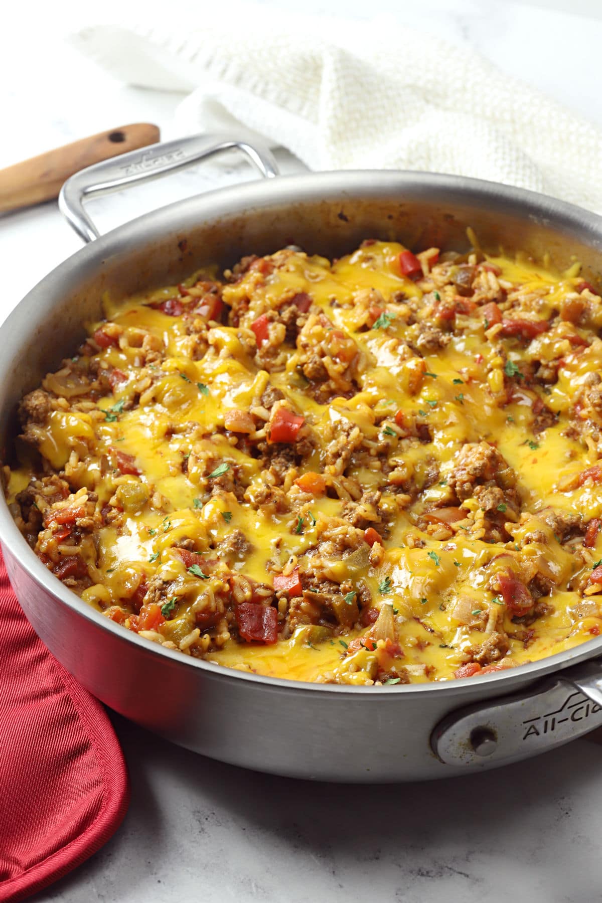 Saute pan filled with beef, rice, and melted cheese.