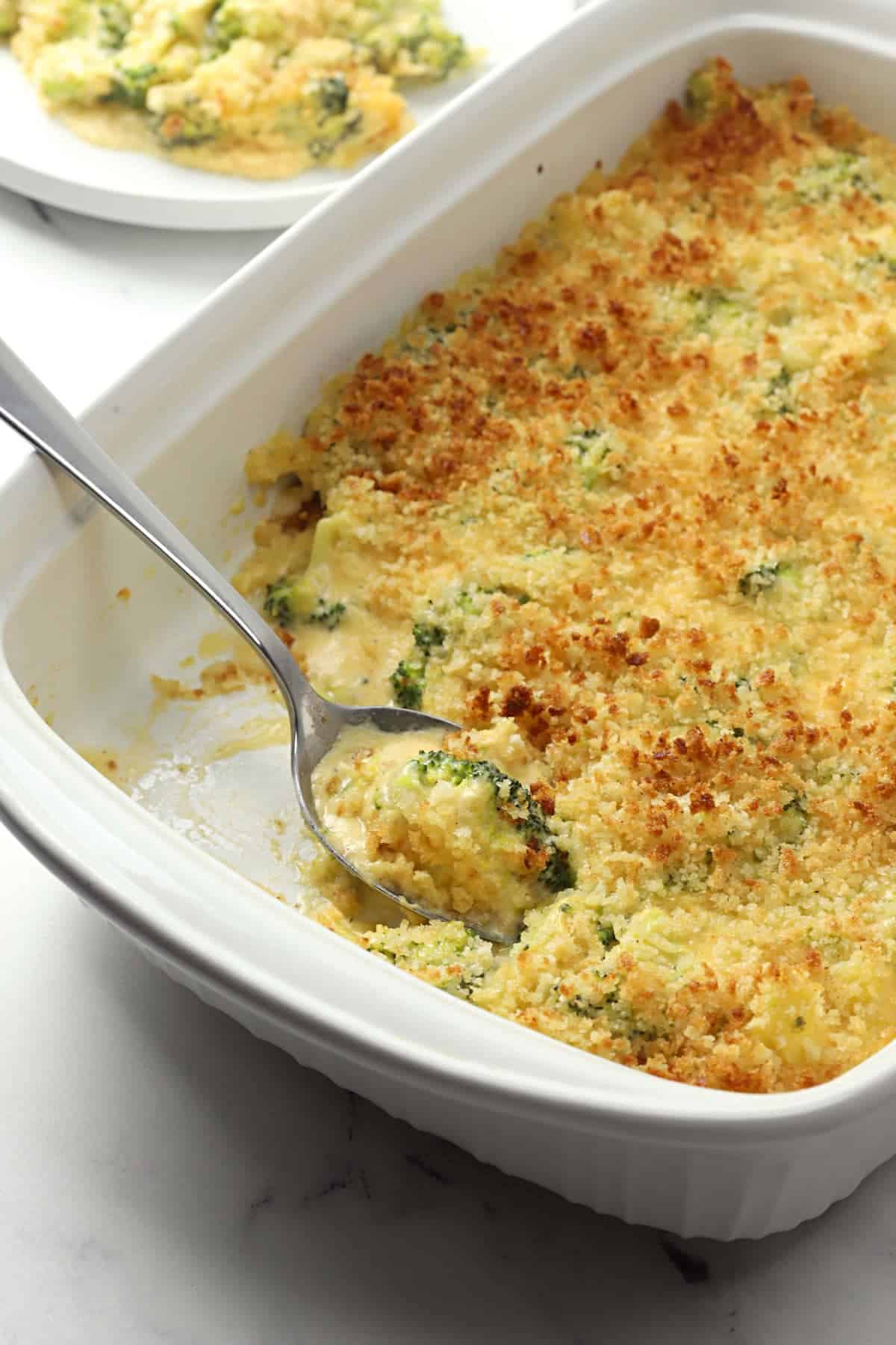 Broccoli and cheese topped with panko crust in a white casserole dish.
