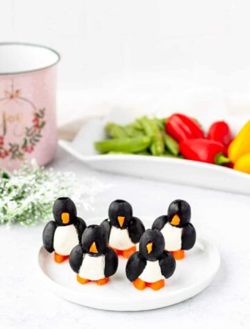 Olive penguin appetizers on a white serving plate.