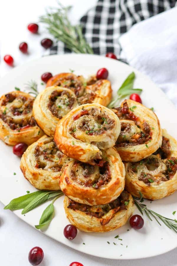 Sausage cranberry brie bites on a white serving plate.