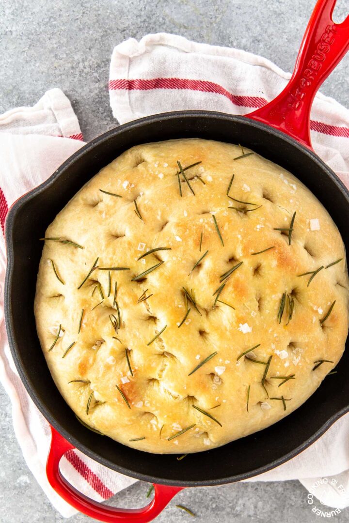 Cast iron skillet filled with focaccia bread topped with rosemary.