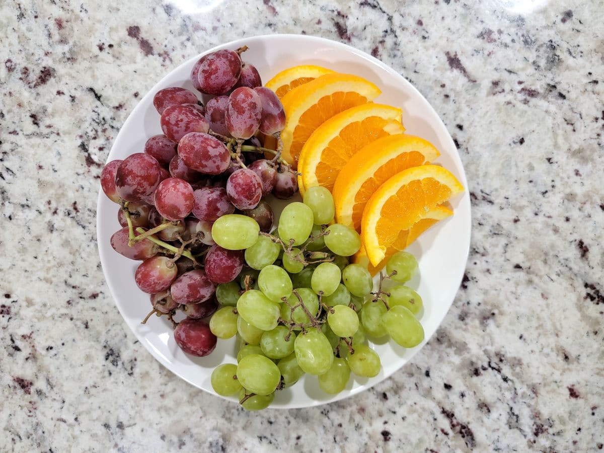 Grapes and orange slices on a plate.
