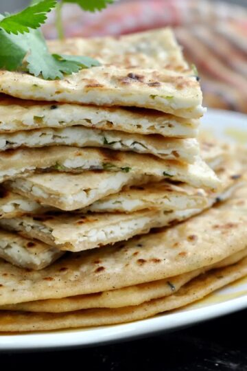 Sliced stuffed paneer flatbread stacked on a white plate.