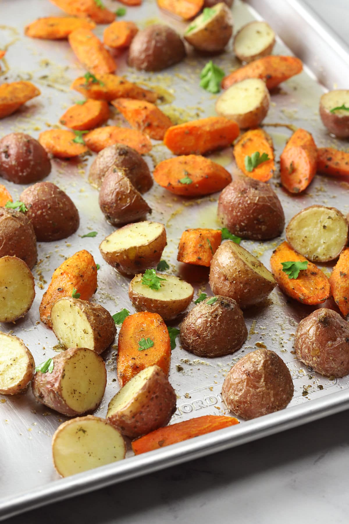 Roasted potatoes and carrots on a metal sheet pan.