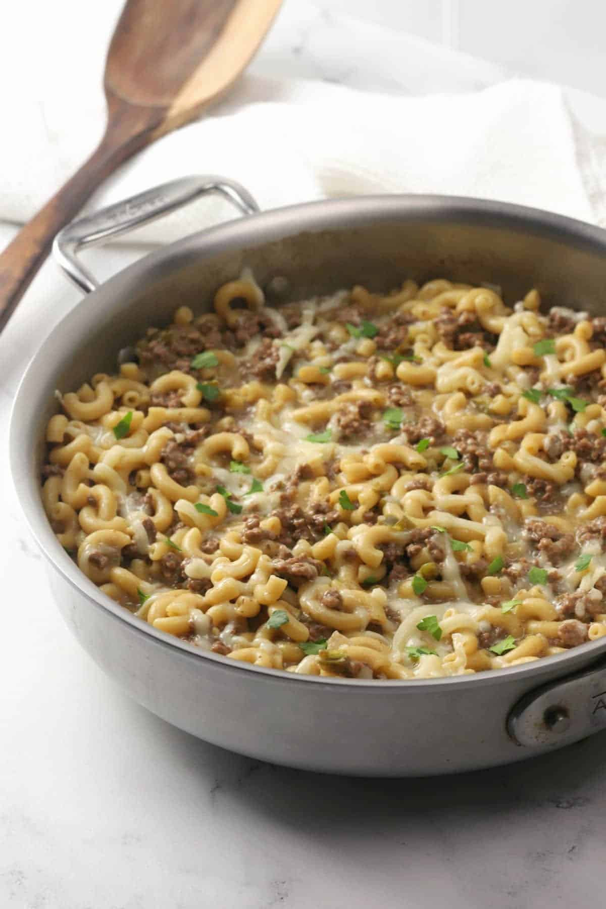 Saute pan filled with ground beef and pasta in cheesy sauce.