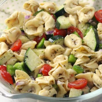 Glass bowl filled with tortellini pasta salad.