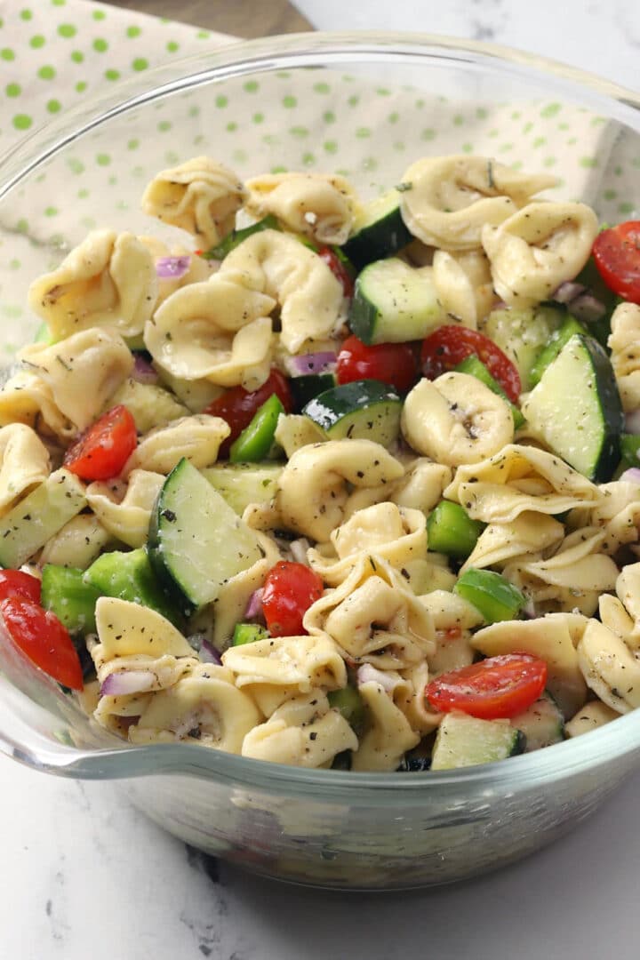 Glass bowl filled with tortellini pasta salad.