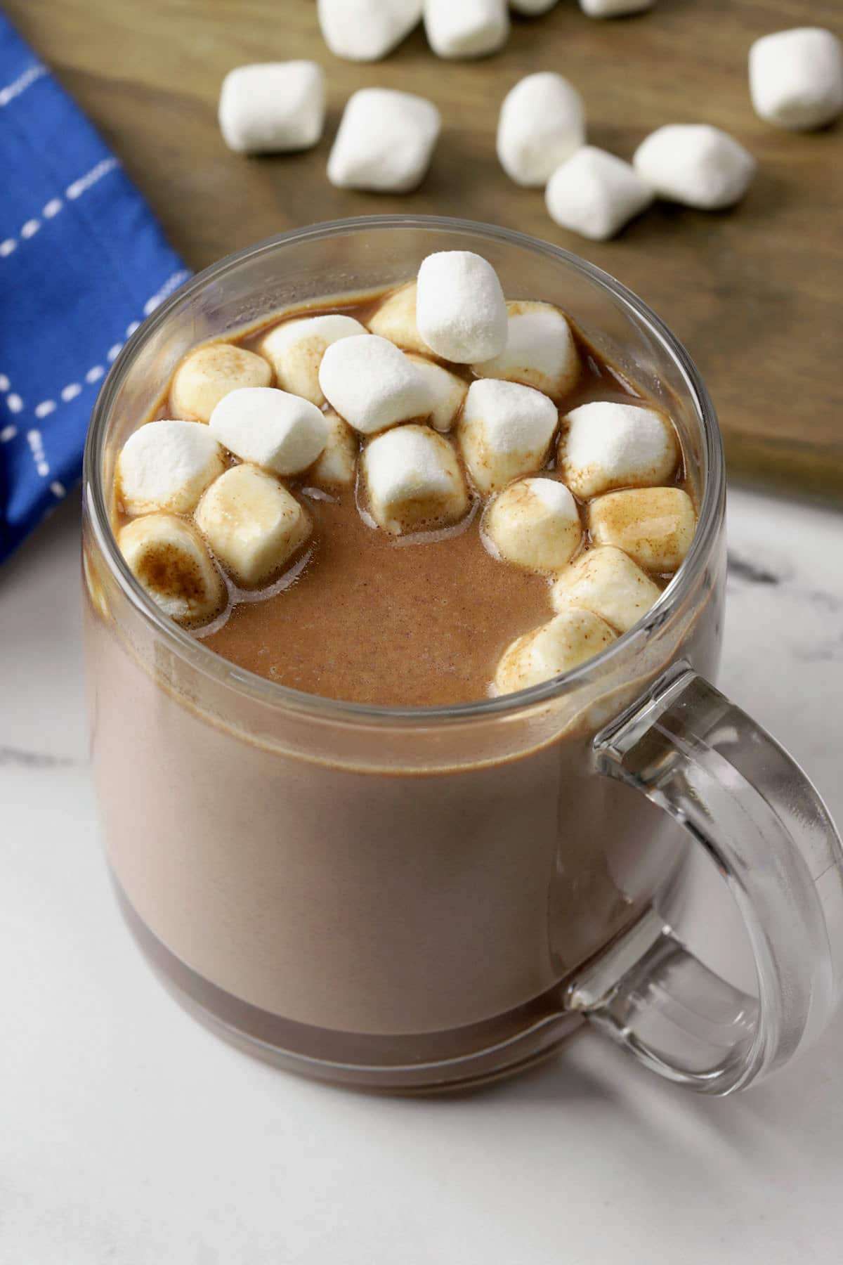 Glass mug of hot chocolate topped with mini marshmallows.