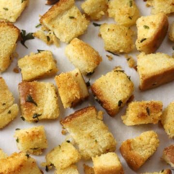 Garlic butter croutons on a parchment lined baking sheet.